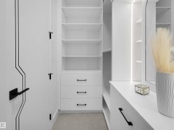 Custom closet system featuring built-in shelving, multiple drawers with matte black hardware, and integrated vertical lighting - 