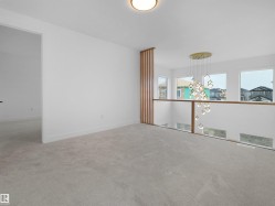 Open concept hallway featuring modern chandelier, light neutral carpet, white walls, and a wood slat accent wall - 