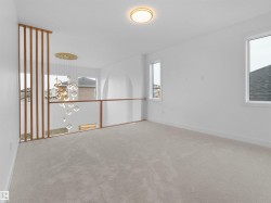 Spacious loft area featuring light-toned carpet, white walls, and multiple windows - 