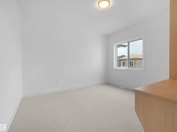 Bright room featuring neutral carpeting, a large window, white trim, and a built-in wood-finish desk - 