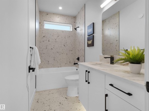 Contemporary bathroom featuring a white vanity with a light-toned countertop, integrated sink, and matte black fixtures - 43 Eldridge Point(E), St. Albert, AB - Indoor Photo Showing Bathroom