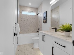 Contemporary bathroom featuring a white vanity with a light-toned countertop, integrated sink, and matte black fixtures - 