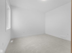 Bright interior space featuring a window with white trim, light-toned carpeting, white walls, and white baseboards - 