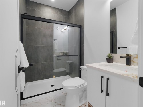 Contemporary bathroom featuring a walk-in shower with black-framed glass enclosure, grey large-format tile walls, and a white shower pan - 43 Eldridge Point(E), St. Albert, AB - Indoor Photo Showing Bathroom