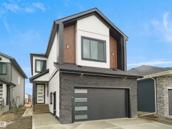 Contemporary exterior featuring black stacked stone, white horizontal siding, and wood-finish paneling - 