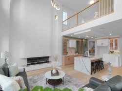 Spacious living area featuring a double-height ceiling, built-in electric fireplace, and light wood-finish flooring - 