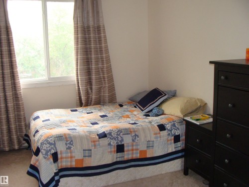 Bedroom featuring a window with white trim, carpeting, and light-toned walls - 401 10326 117 Street, Edmonton, AB - Indoor Photo Showing Bedroom