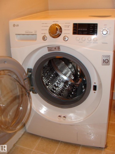 Front-load washing machine with a stainless steel drum and clear glass door - 401 10326 117 Street, Edmonton, AB - Indoor Photo Showing Laundry Room