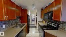 Galley kitchen featuring wood cabinetry, a mosaic tile backsplash, double basin stainless steel sink, and light-toned countertops - 401 10326 117 Street, Edmonton, AB  - Indoor Photo Showing Kitchen With Double Sink 