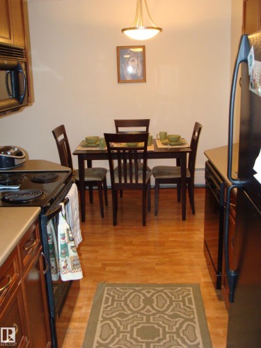 Kitchen and dining area featuring wood-finish flooring - 401 10326 117 Street, Edmonton, AB - Indoor Photo Showing Dining Room