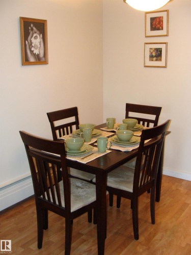 Dining area featuring wood-finish flooring and a corner-mounted ceiling light fixture - 401 10326 117 Street, Edmonton, AB - Indoor Photo Showing Dining Room