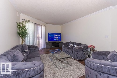 Spacious living area featuring wood-finish flooring, light-toned walls, and crown molding - 214 13005 140 Avenue, Edmonton, AB - Indoor Photo Showing Living Room