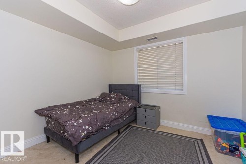 Interior space featuring neutral wall paint, carpet flooring, a window with blinds, and white trim - 214 13005 140 Avenue, Edmonton, AB - Indoor Photo Showing Bedroom