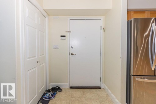 Entryway featuring a white paneled bi-fold closet, a white entry door, light beige wall paint, and light-toned floor tiling - 214 13005 140 Avenue, Edmonton, AB - Indoor Photo Showing Other Room
