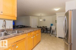 Kitchen with wood-finish cabinetry, a double basin stainless steel sink, and a textured countertop - 