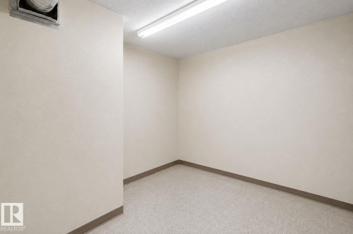 Versatile room featuring light neutral wall paint, speckled flooring, and a drop ceiling with fluorescent lighting - 204 278 Suder Greens Drive, Edmonton, AB - Indoor Photo Showing Other Room