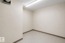Versatile room featuring light neutral wall paint, speckled flooring, and a drop ceiling with fluorescent lighting - 