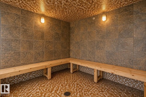 Tiled room featuring corner wooden benches, textured mosaic ceiling, and two wall-mounted light fixtures - 204 278 Suder Greens Drive, Edmonton, AB - Indoor Photo Showing Other Room
