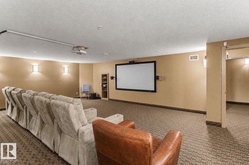Dedicated media room featuring a large projector screen, ceiling-mounted projector, and integrated wall sconces - 204 278 Suder Greens Drive, Edmonton, AB - Indoor Photo Showing Other Room