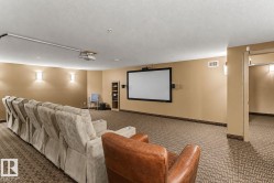 Dedicated media room featuring a large projector screen, ceiling-mounted projector, and integrated wall sconces - 