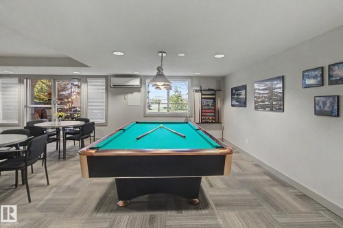 Recreation room featuring a pool table with an overhead pendant light, multiple large windows with horizontal blinds, and patterned carpet flooring - 204 278 Suder Greens Drive, Edmonton, AB - Indoor Photo Showing Other Room