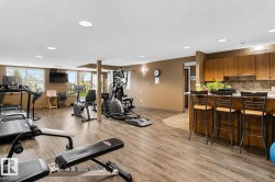 Fitness center with wood-finish flooring, recessed lighting, and a snack bar featuring wood cabinetry and a tile backsplash - 
