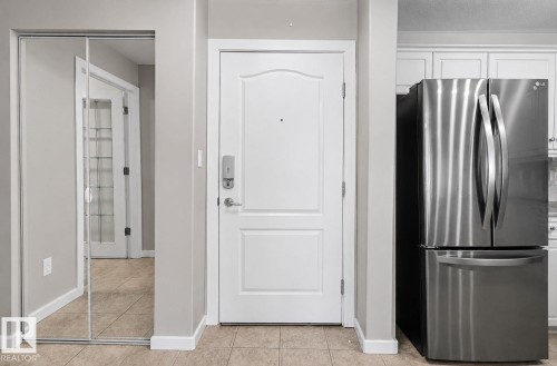 Entryway featuring a paneled door with smart lock hardware, mirrored closet doors, and tile flooring - 204 278 Suder Greens Drive, Edmonton, AB - Indoor Photo Showing Other Room
