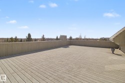Expansive rooftop deck featuring composite decking and a solid perimeter wall - 