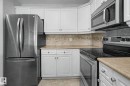 Kitchen featuring white cabinetry, stainless steel appliances, a tile backsplash, and light-toned countertops - 204 278 Suder Greens Drive, Edmonton, AB  - Indoor Photo Showing Kitchen 
