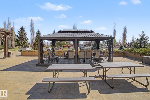 Expansive paved patio area featuring a central gazebo with a metal roof and privacy curtains - 204 278 Suder Greens Drive, Edmonton, AB - Outdoor With Deck Patio Veranda