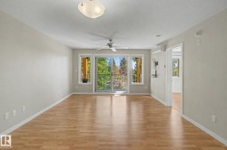 Bright living area featuring wood-finish flooring, a contemporary ceiling fan, and a ceiling-mounted light fixture - 