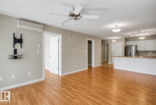 Spacious main living area featuring wood-finish flooring and neutral-toned walls - 204 278 Suder Greens Drive, Edmonton, AB - Indoor Photo Showing Kitchen