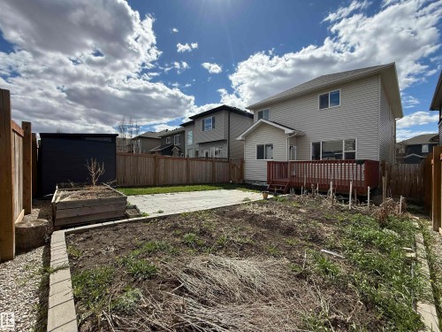 Expansive backyard featuring a wood privacy fence, a wooden raised garden bed, a paver patio area, and a black storage shed - 4875 Wright Drive, Edmonton, AB - Outdoor