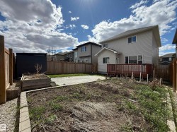 Expansive backyard featuring a wood privacy fence, a wooden raised garden bed, a paver patio area, and a black storage shed - 