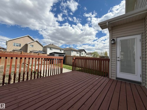 Spacious wooden deck with a contrasting railing, offering direct access to the backyard through a glass-paneled door - 4875 Wright Drive, Edmonton, AB - Outdoor With Deck Patio Veranda With Exterior