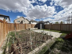 Private backyard featuring wood fencing, a paved patio area, and raised garden beds - 