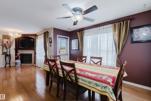 Interior dining area featuring wood-finish flooring, a ceiling fan with integrated lighting, and a window with blinds and drapes - 1764 Melrose Crescent, Edmonton, AB 