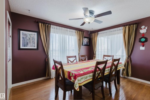Dining area featuring wood-finish flooring, a ceiling fan with integrated lighting, and multiple windows with sheer and opaque drapery - 1764 Melrose Crescent, Edmonton, AB 