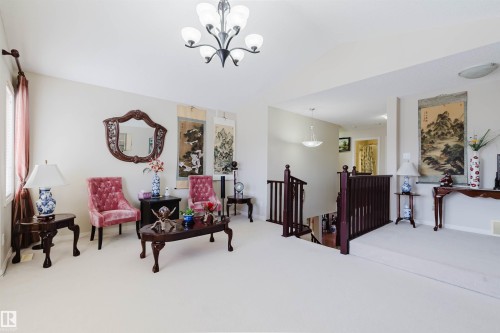 Upper-level landing featuring light-colored carpet, a chandelier, and a wood staircase with balusters - 1764 Melrose Crescent, Edmonton, AB 