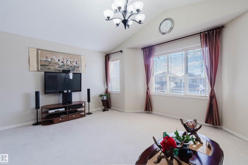 Spacious room featuring vaulted ceilings, light-toned carpeting, and a large window with blinds - 1764 Melrose Crescent, Edmonton, AB 