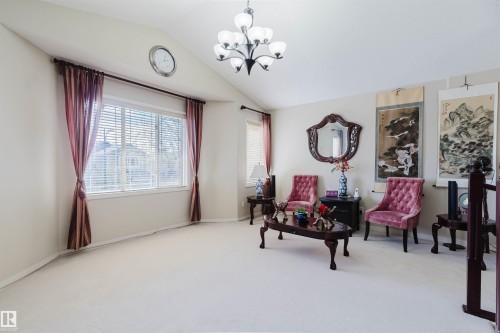 Vaulted ceiling living area featuring a large window, white carpeting, and an overhead chandelier - 1764 Melrose Crescent, Edmonton, AB 