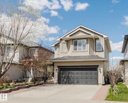 Two-story residential exterior featuring beige siding, white trim, and a dark asphalt shingle roof - 1764 Melrose Crescent, Edmonton, AB 