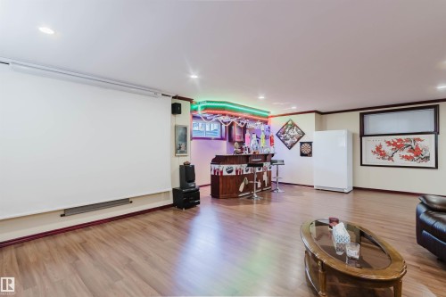 Entertainment space featuring a retractable projection screen, wood-finish flooring, recessed lighting, and a built-in bar with accent lighting - 1764 Melrose Crescent, Edmonton, AB 
