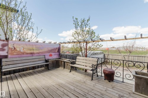 Spacious outdoor deck featuring natural wood planks, a decorative metal railing, and built-in wooden planters - 1764 Melrose Crescent, Edmonton, AB 