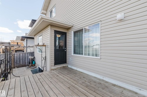 Expansive wood deck with wrought iron railing, light-colored siding, and a black exterior door with glass insert - 1764 Melrose Crescent, Edmonton, AB 