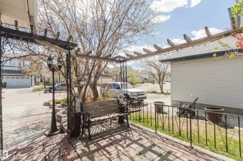 Paved patio area featuring a wooden pergola and a wrought iron railing - 1764 Melrose Crescent, Edmonton, AB 