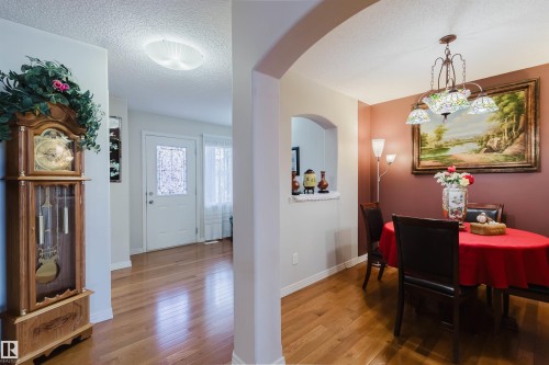 Dining area with a decorative chandelier, archway feature, and wood-finish flooring - 1764 Melrose Crescent, Edmonton, AB 