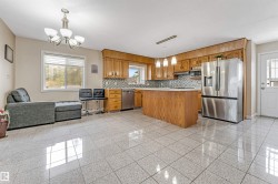 Spacious kitchen featuring a central island, wood cabinetry, stainless steel appliances, and a patterned tile backsplash - 