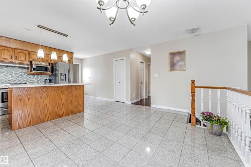 Kitchen featuring wood cabinetry, stainless steel appliances, a tile backsplash, and a breakfast bar with pendant lighting - 1529 49A Street Nw, Edmonton, AB - Indoor Photo Showing Kitchen
