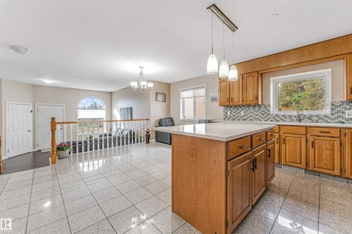 Kitchen featuring a central island with countertop, natural wood cabinetry, a mosaic tile backsplash, and a window above the sink - 1529 49A Street Nw, Edmonton, AB - Indoor Photo Showing Kitchen